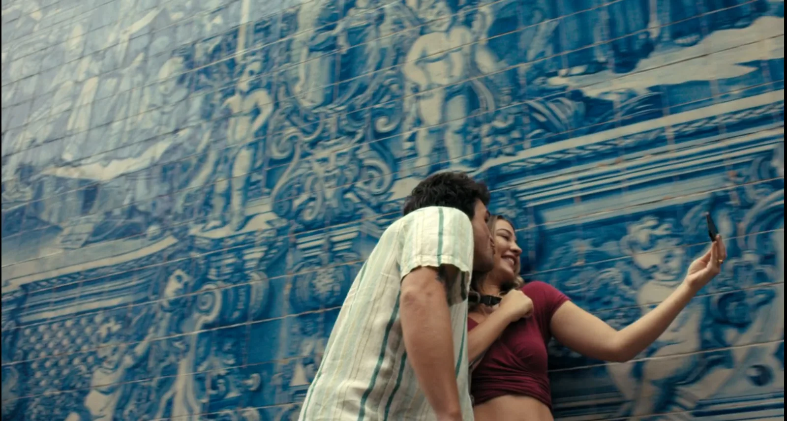 O casal se diverte enquanto faz vídeos mostrando o átrio de azulejos da Estação de São Bento. Foto: Reprodução do filme O mapa que me leva até você da Amazon Prime Video.